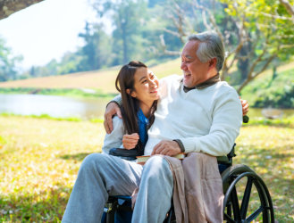 Caregiver hugging the elderly man on a wheelchair